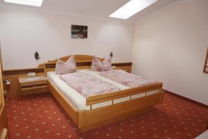 ein Schlafzimmer mit einem großen Holzbett mit rosa Kissen in der Unterkunft Haus Troger in Milders