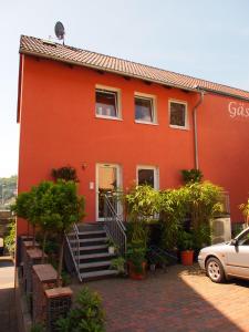 a red house with stairs and a car parked in front at Gastehaus Weingut Rossler in Lorch am Rhein