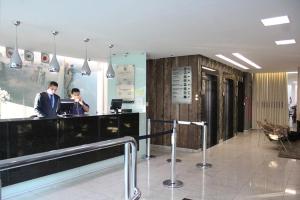 two people working at a desk in a lobby at Excellence Comfort Hotel in Divinópolis