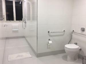 a white bathroom with a toilet and a shower at Xikus Palace Hotel in Guanhães