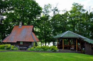a small cabin with a red roof in a yard at Pērkonu namiņš in Balvi