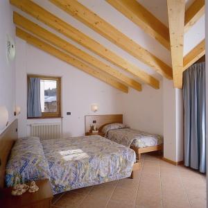 1 dormitorio con 2 camas en una habitación con techos de madera en Residence Alba Nova, en Andalo