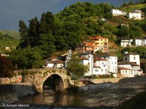 a bridge over a river with houses on a hill at Hostal los nogales in Cangas del Narcea