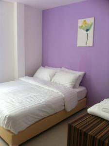 a bedroom with a bed and a purple wall at Nantra Ekamai Hotel in Bangkok