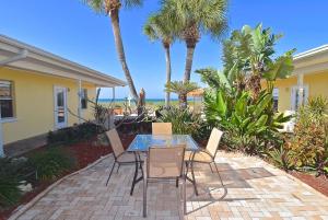 a patio with a glass table and chairs and palm trees at A Beach Retreat on Casey Key in Venice