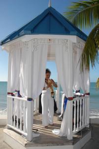 a bride and groom standing under a gazebo on the beach at Villa Beach Cottages in Castries