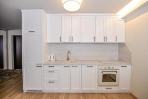 a kitchen with white cabinets and a sink at IN24 in Palanga