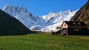 a house in a field with a snow covered mountain at Fifth Season in Jut'a