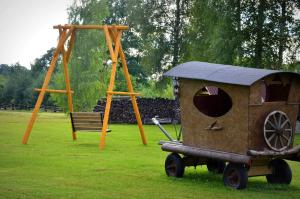 a play area with a wooden toy train and a swing at Pērkonu namiņš in Balvi