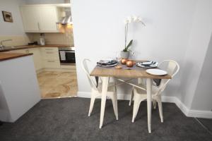 a kitchen with a wooden table with chairs and a tableweredotent at The Courtyard Apartment in Leamington Spa