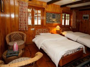 1 dormitorio con 2 camas, silla y ventanas en Mountain Lodges of Nepal - Phakding, en Phakding