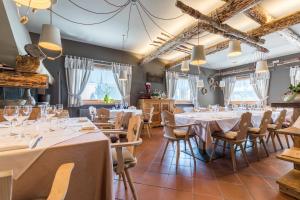 a restaurant with white tables and chairs and windows at La capr'allegra in Gallio