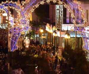 una multitud de personas caminando por una calle con luces de Navidad en Hotel Sollievo, en San Giovanni Rotondo