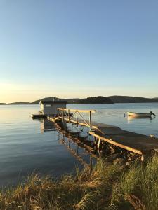 a dock on a lake with two boats in the water at Anfasteröd Gårdsvik - badstugor med loft in Ljungskile