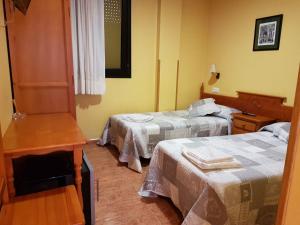 a hotel room with two beds and a table at Hostal los nogales in Cangas del Narcea +33 photos