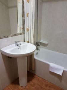 a white bathroom with a sink and a bath tub at Hostal los nogales in Cangas del Narcea