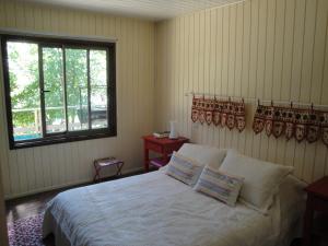 a bedroom with a bed with white sheets and a window at Casa Orilla Lago in Villarrica