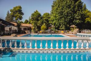 a swimming pool with a white fence and trees at Cabañas Alpendorf in Villa General Belgrano