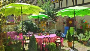 una mesa y sillas con sombrillas verdes en un jardín en La Tour Enchantée, en Ribeauvillé