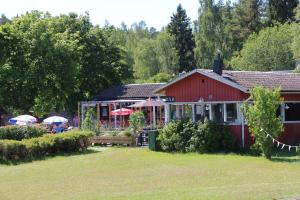 un edificio rojo con gente sentada fuera de él en Rösjöbaden Camping & Stugby en Sollentuna