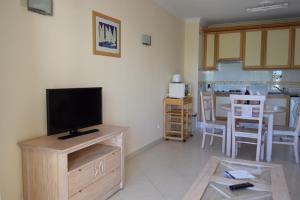 a living room with a television and a kitchen at Vila Marachique in Alvor