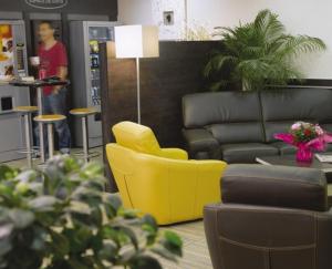 sala de estar con silla amarilla y sofá en Hôtel Akena City Albi Gaillac, en Brens