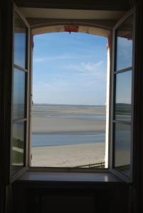 een open raam met uitzicht op het strand bij Hotel Restaurant Les Tourelles in Le Crotoy