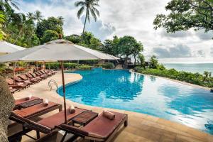 a swimming pool with lounge chairs and an umbrella at Panviman Resort Koh Phangan - SHA Extra Plus in Thong Nai Pan Noi