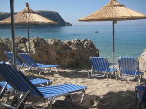 a group of chairs and umbrellas on a beach at Mare Beachfront Rooms Himare in Himare