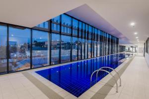 a large swimming pool in a building with windows at Ibis Styles Hobart in Hobart
