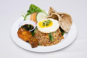 a white plate of food with an egg and fried food at Hotel Seri Malaysia Seremban in Seremban