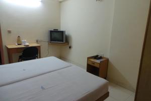 een kleine kamer met een bed en een televisie bij Hotel Span in Kozhikode