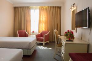 a hotel room with two beds and a desk at Hotel Seri Malaysia Kulim in Kulim