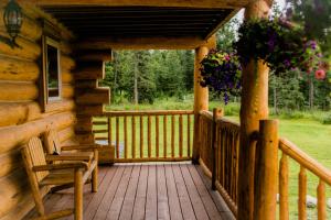 a porch of a log cabin with chairs and flowers at Alaska Knotty Pine B&B in Palmer