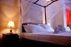 a bedroom with a canopy bed and a lamp at Royal Majesty Bungalow in Hatton