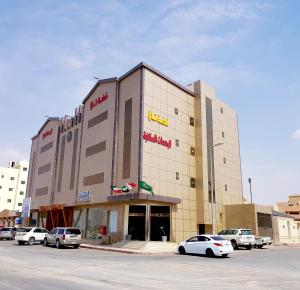 a large building with cars parked in a parking lot at فضة تالا للشقق المخدومة 1 in Buraydah