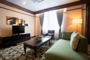 a living room with a green couch and a television at Hotel Seri Malaysia Lawas in Lawas