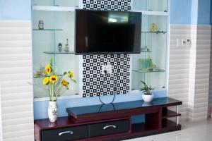 a living room with a tv and a table with flowers at Hue Lovely Homestay in Hue