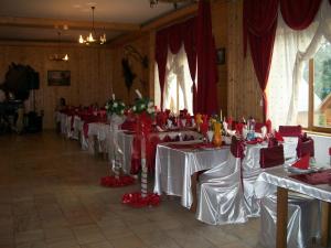 une rangée de tables dans une pièce avec des réglages de table rouge et blanc dans l'établissement Complex Dracula & Spa, à Căpăţîneni-Ungureni