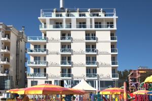 um edifício alto e branco com guarda-chuvas à frente em Residence Terminus em Rimini