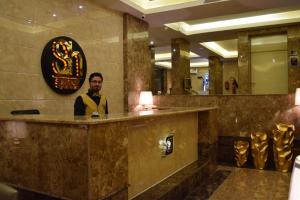 a man standing behind a bar in a hotel lobby at Al Shiraz Suites in Muhayil