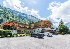 budynek z dwoma samochodami zaparkowanymi na parkingu w obiekcie Hotel Künstleralm w Kaprunie