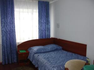 a bedroom with a bed and a window with blue curtains at Hotel Berezka in Vyshny Volochyok