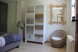 a bedroom with a glass cabinet with a chair and a mirror at Le Charme des Dunes in Arcachon