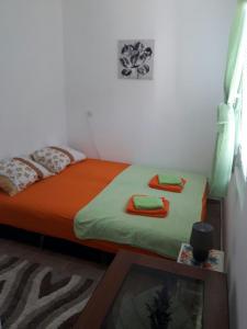 a bedroom with a bed with orange sheets and towels at Apartman Nikocevic in Dobra Voda