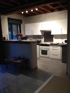 a kitchen with white cabinets and a bench in it at La grange de la vallée in Hamars