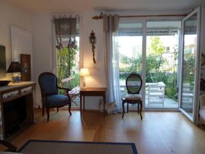 een woonkamer met een bureau en stoelen en glazen schuifdeuren bij Ferienwohnung Bella Rosa in Freiburg im Breisgau