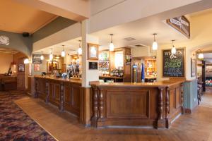 a bar in a pub with wooden cabinets at Heart of England, Northampton by Marston's Inns in Daventry