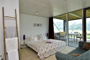 sypialnia z łóżkiem, kanapą i stołem w obiekcie Glas House - Design Holiday Home w mieście Piesendorf