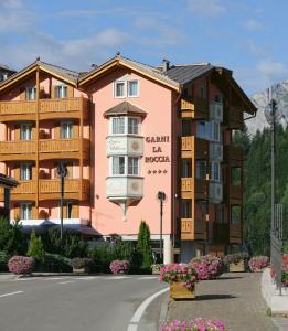 a pink building with a balcony on a street at Hotel Garni La Roccia in Andalo
